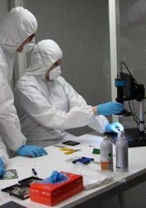 Data recovery engineers examining hard drive heads in cleanroom