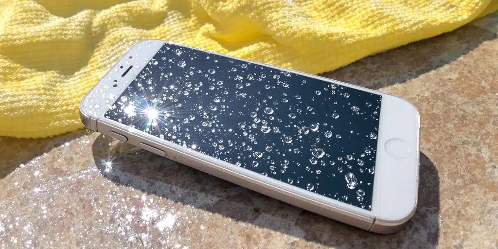 Wet iPhone on pool edge with water droplets visible