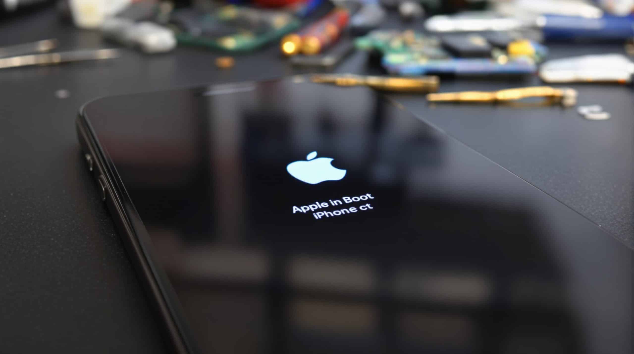 iPhone stuck on Apple logo with repair tools nearby