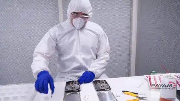 Technician in a coverall performing a hard drive head swap on the bench