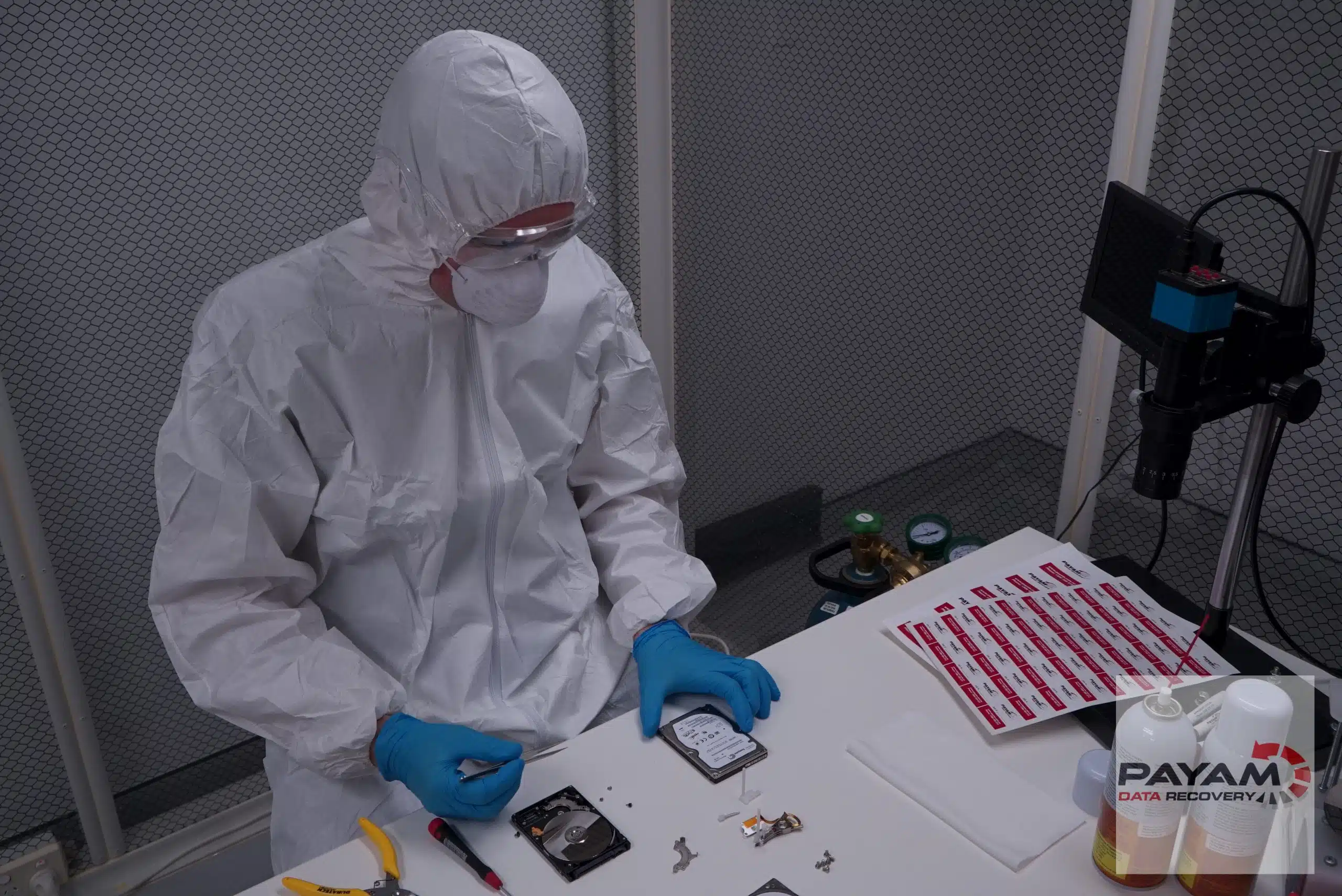 Technician in a coverall working on a hard drive inside the laminar flow cabinet