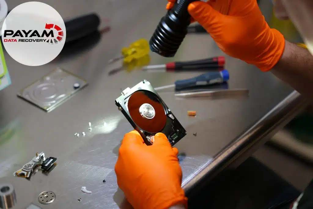 Engineer in gloves inspecting hard drive platters with a torch before a head swap