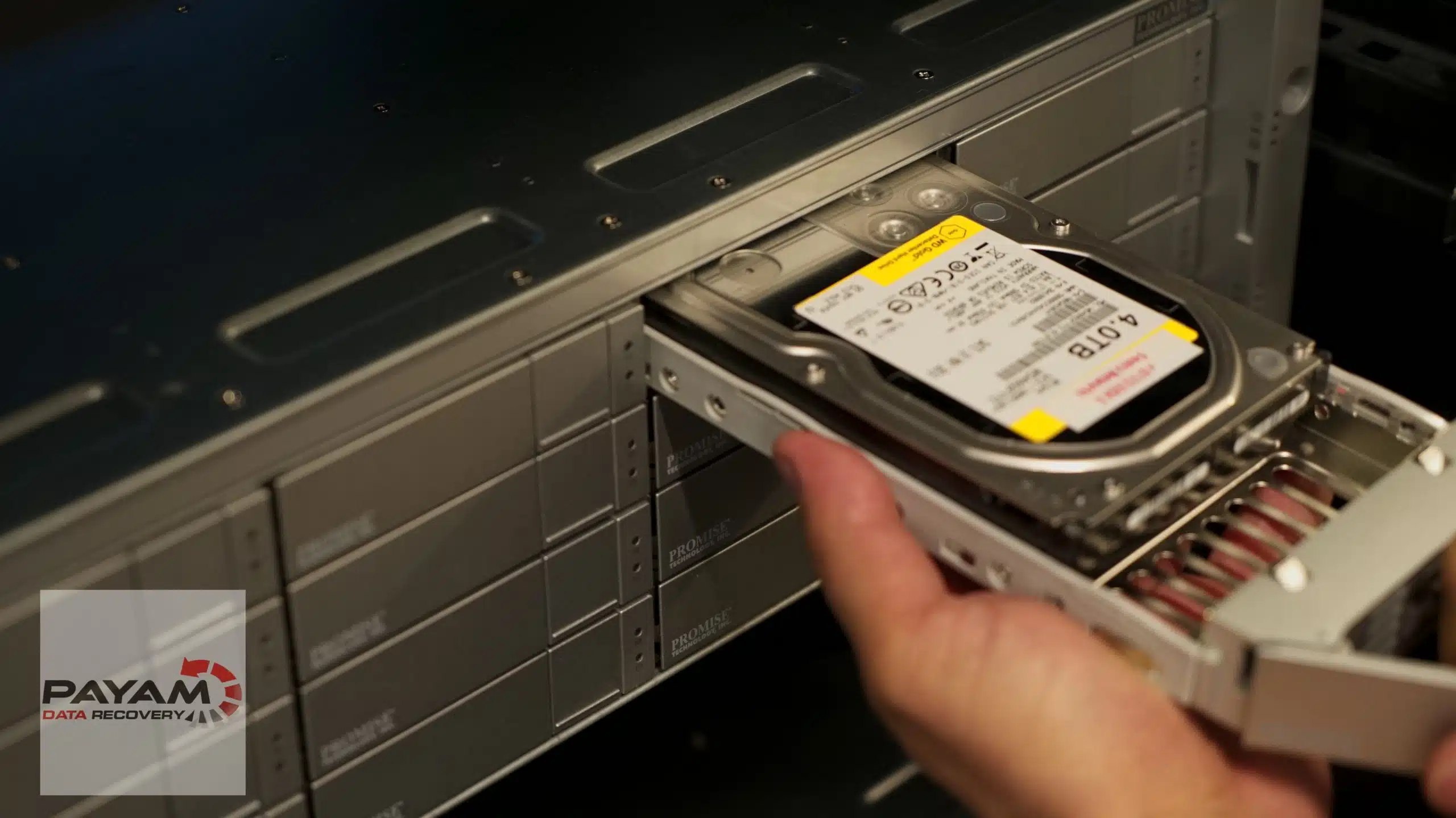 Hand inserting a hard drive caddy into a server rack drive bay