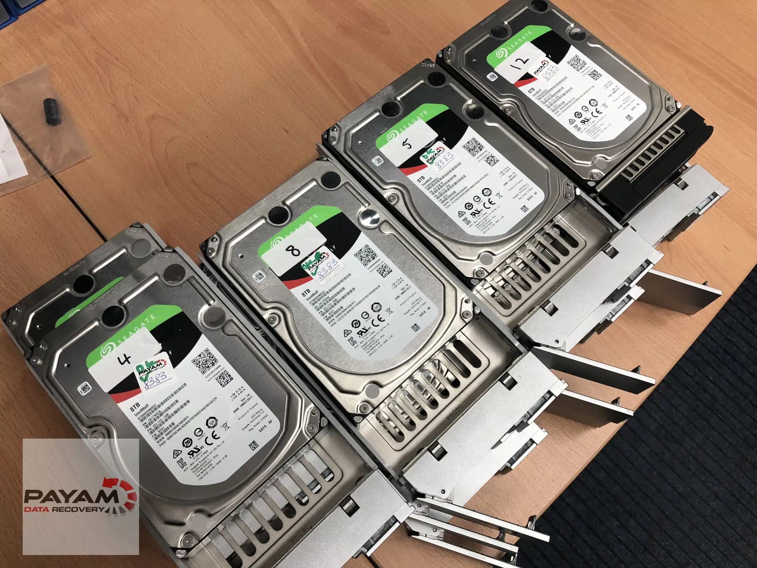 Four hard drives with green recovered tags lined up on the lab bench