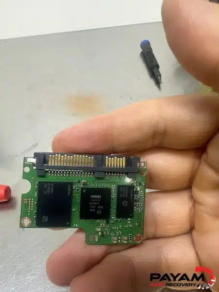 Technician holding a small SSD circuit board with a soldered wire attached