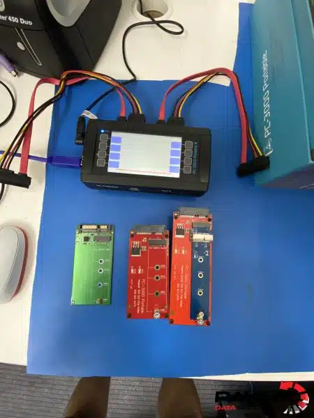 PC-3000 Portable III connected by SATA cables, with three SSD adapter boards on a blue mat