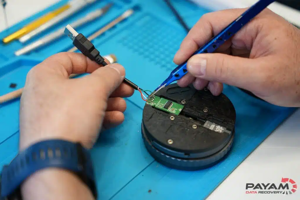 Engineer soldering the circuit board of a broken USB flash drive